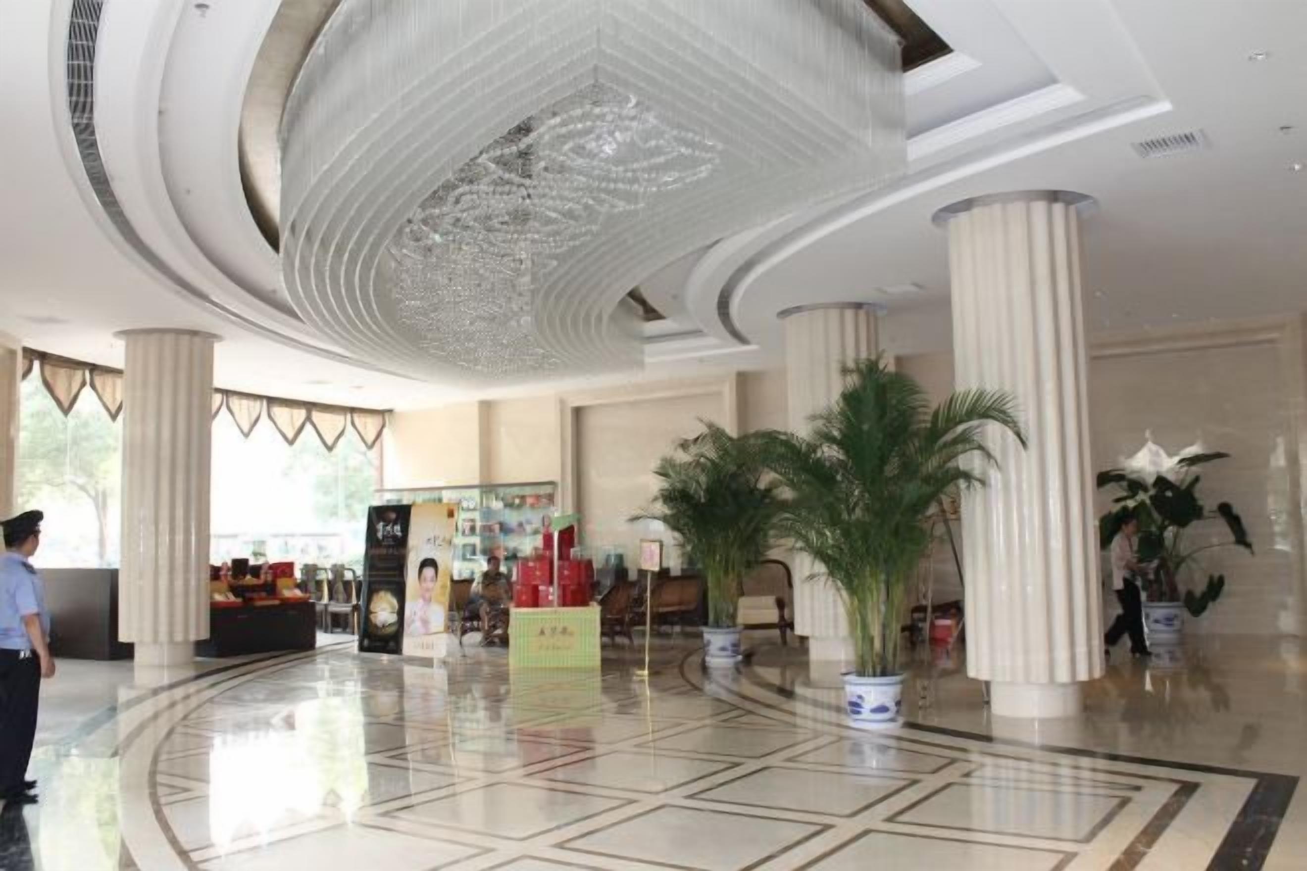 A lobby with a high ceiling, large columns, and a central plant arrangement.