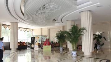 A lobby with a high ceiling, large columns, and a central plant arrangement.