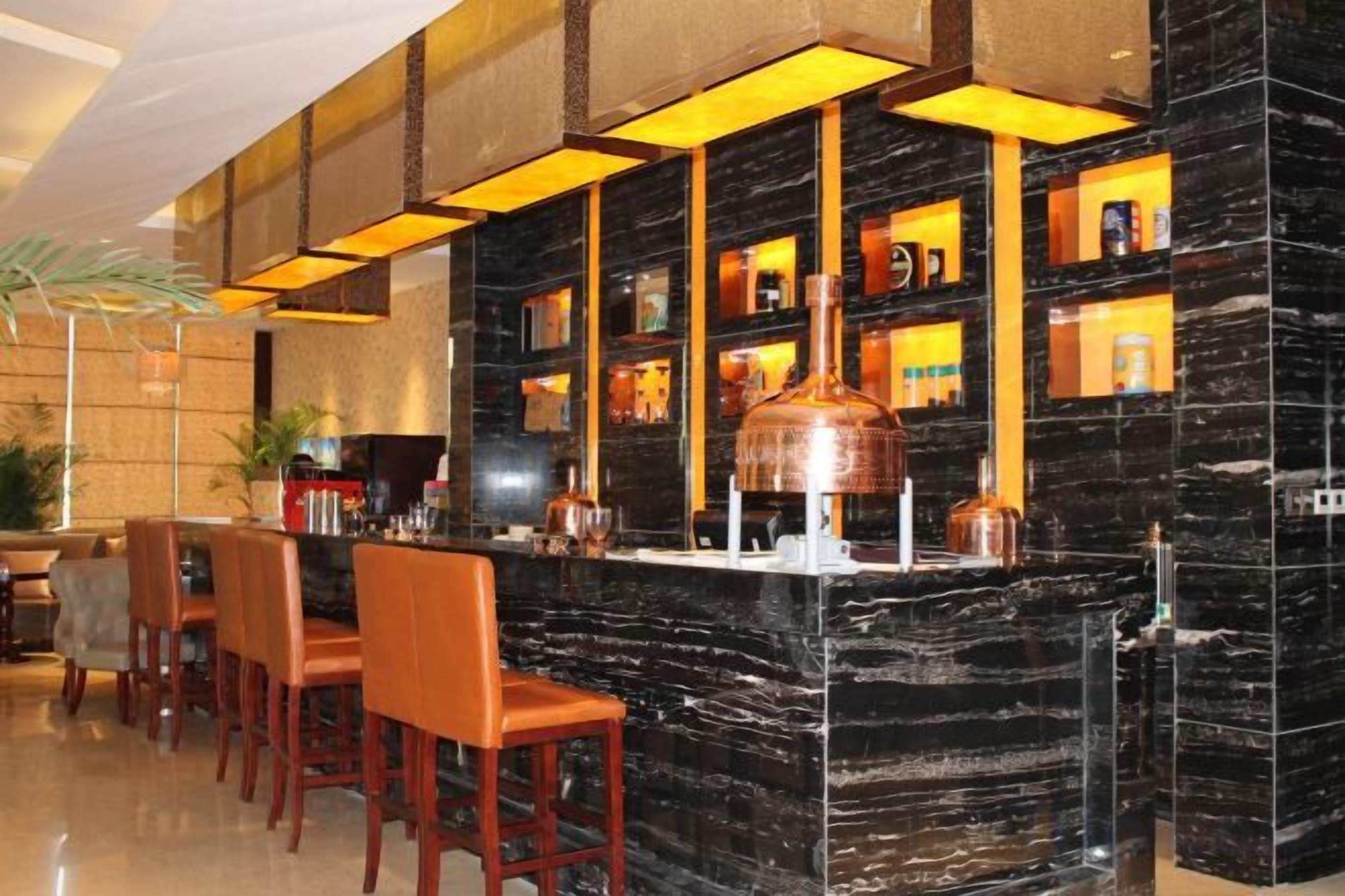 A bar area with a marble counter, multiple seating options, and shelves with bottles.