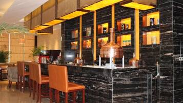 A bar area with a marble counter, multiple seating options, and shelves with bottles.
