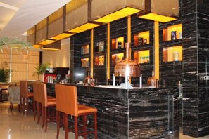 Een bar met een marmeren toonbank, diverse zithoeken en planken vol flessen.
