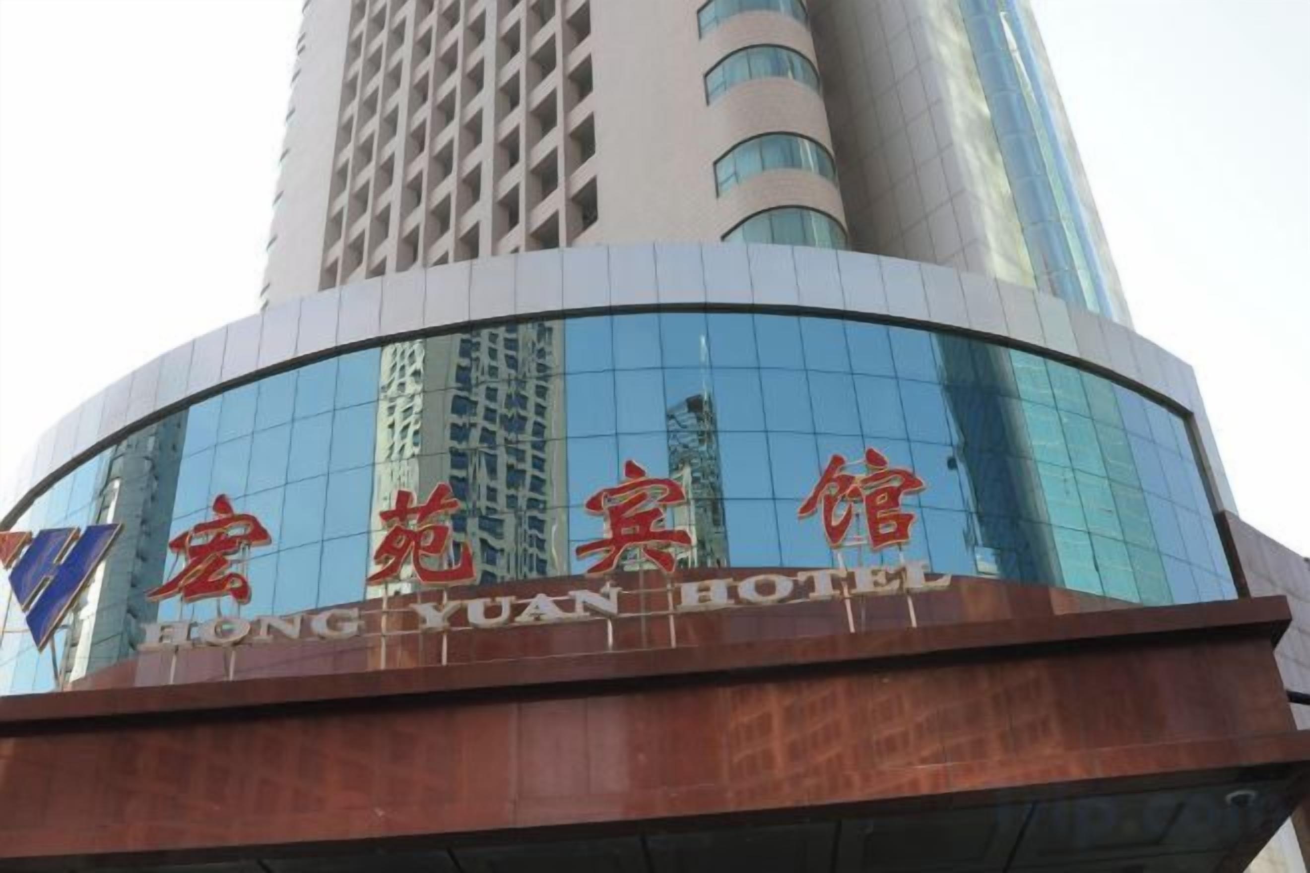 A hotel with a modern glass facade and a sign in red characters.
