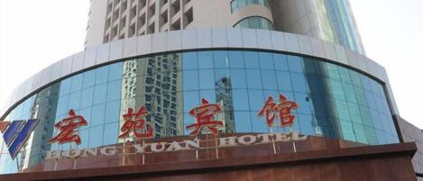 A hotel with a modern glass facade and a sign in red characters.