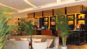 Eine moderne Lobby mit einer gebogenen Couch, einem weißen Sessel und einer Zimmerpflanze.