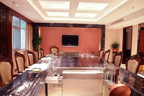 A conference room with a long table, chairs, a television, and a plant. - Hongyuan Hotel (Shijiazhuang)