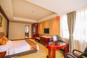 Een hotelkamer met een bed, een bureau, een stoel, een televisie en een raam met gordijnen.