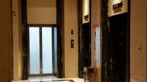 Eine Hotelhalle mit einer großen Glastür, einem Marmorboden und einem kleinen Holztisch.