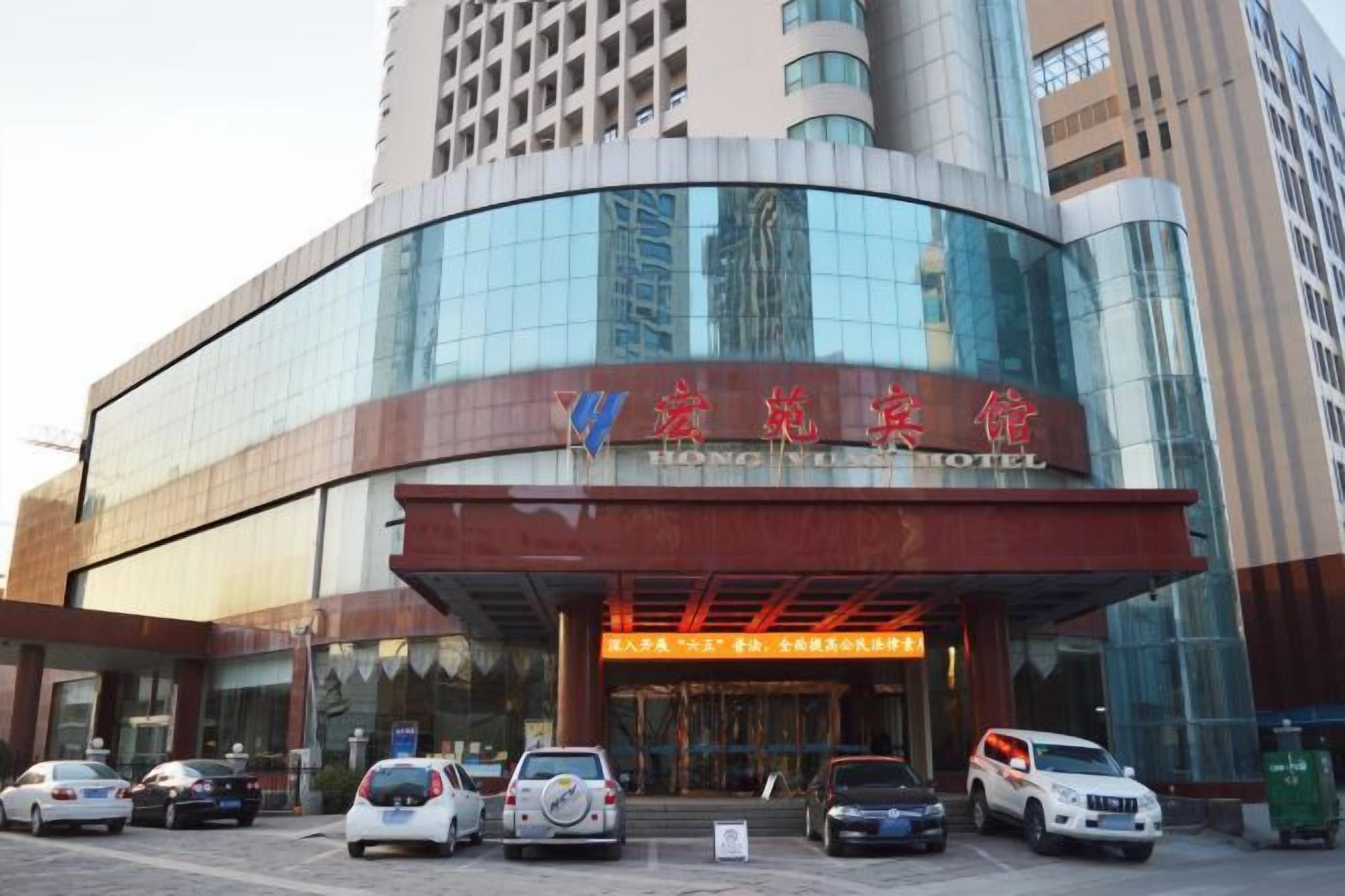 A modern hotel with a curved facade, multiple parking spaces, and a prominent entrance.