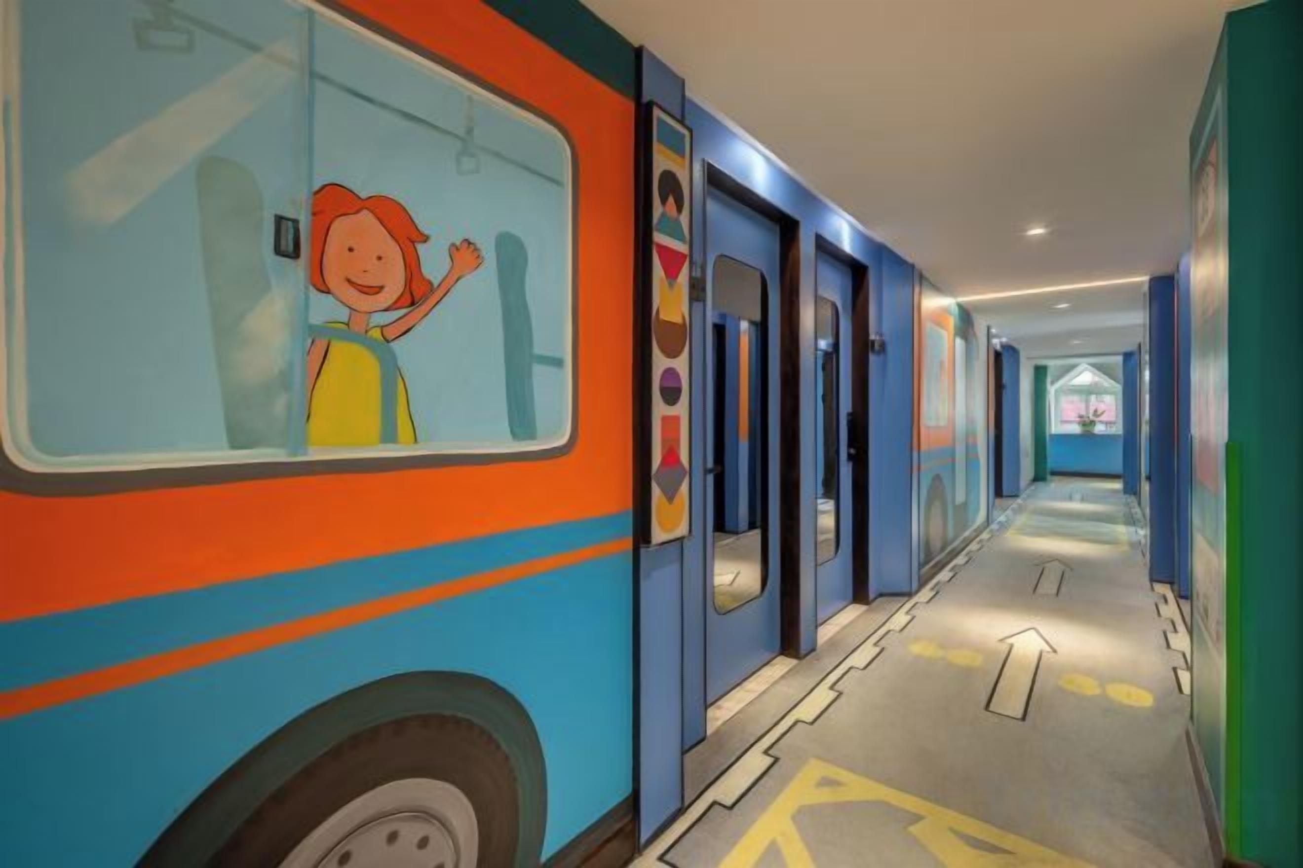 A corridor with a bus mural, doors, and directional arrows on the floor.