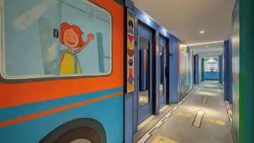 A corridor with a bus mural, doors, and directional arrows on the floor.