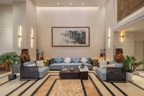 A spacious lobby with a large sofa set, a coffee table, and decorative plants. - Qunxian Hotel (Guangzhou)