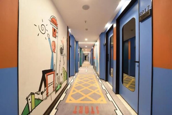 A hotel corridor with doors on the right, a patterned carpet, and a wall with various illustrations. - Qunxian Hotel (Guangzhou)