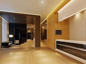 A modern hotel lobby with a wooden floor, a reception desk, and a seating area with a lamp. - Jinjiang Inn Lijiang Qixing Street (Lijiang)