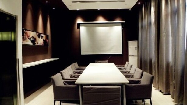 A conference room with a large table, six chairs, a projector screen, and a refrigerator. - Jinjiang Inn Xiamen Hexiang Road West (Xiamen)