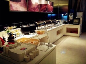 A buffet setup with various food stations, including a hot pot and a salad bar, in a modern hotel setting.