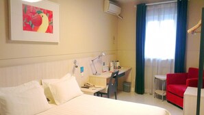 Ein Hotelzimmer mit Bett, Schreibtisch, Stuhl und einem Bild an der Wand.