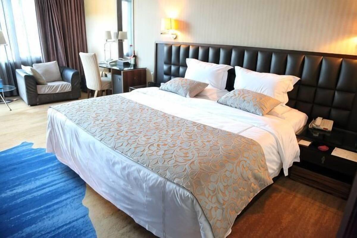 Une chambre d’hôtel avec un grand lit, un bureau, une chaise et une table de chevet.