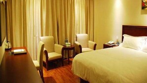 Habitación de hotel con una cama grande, dos sillones, una mesita, una mesita de noche y una cortina.