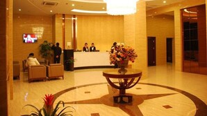 Un hall con una mesa de recepción, una gran araña y un centro de mesa floral.