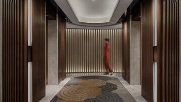 Un pasillo moderno con paneles de madera verticales, alfombra estampada e iluminación empotrada en el techo.