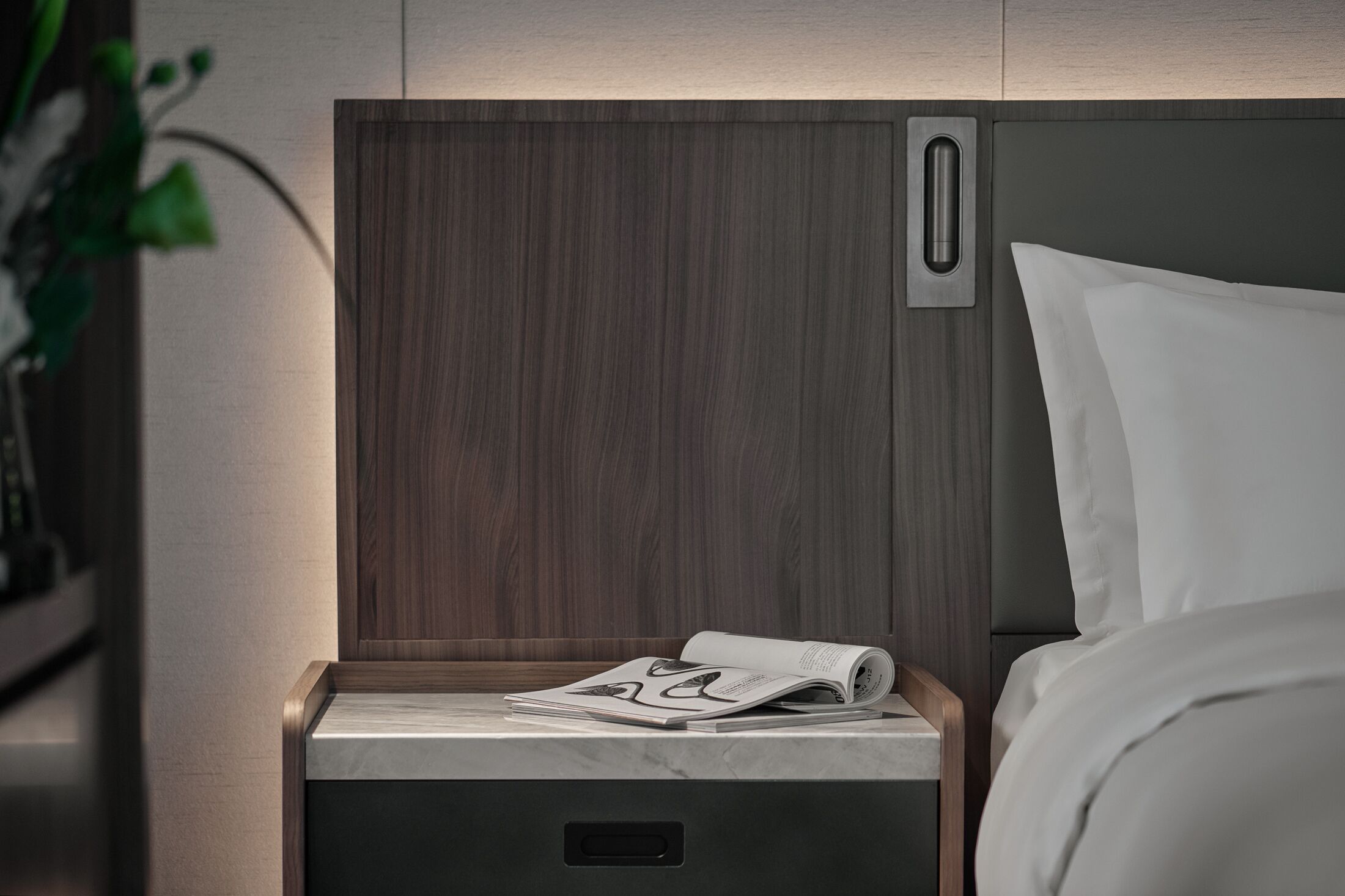 Ein modernes Bett mit Kopfteil und Nachttisch mit einer Zeitschrift.
