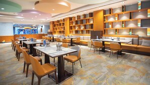 Een moderne hotel lobby met een kinderspeelruimte, zithoeken en een grote boekenkast.