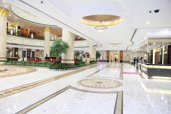 A spacious lobby with a central fountain, multiple levels, and a reception desk.