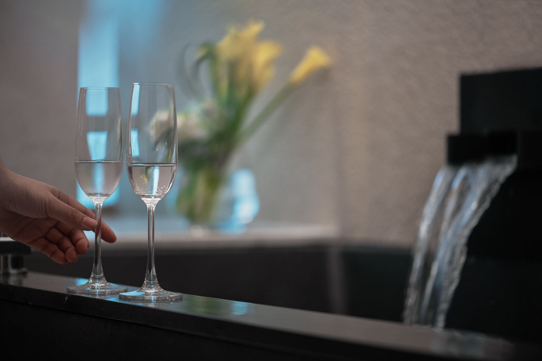 Twee lege glazen op een bar, een hand reikt ernaar.