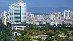 A high-rise building with a clear view of the surrounding cityscape and a park area with pathways and greenery. - Empark Grand Hotel Fuzhou (Fuzhou)