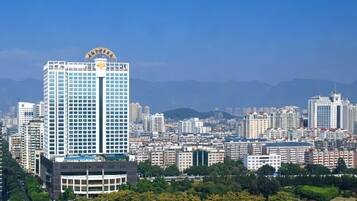 A high-rise building with a clear view of the surrounding cityscape and a park area with pathways and greenery.