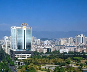 Un immeuble de grande hauteur offrant une vue dégagée sur le paysage urbain environnant, ainsi qu’un espace vert aménagé avec des allées et de la végétation.