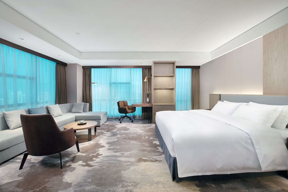 Une chambre d’hôtel moderne avec un grand lit, un canapé, une table basse et un bureau.