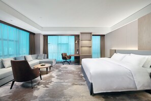 Een moderne hotelkamer met een groot bed, een bank, een salontafel en een bureau.