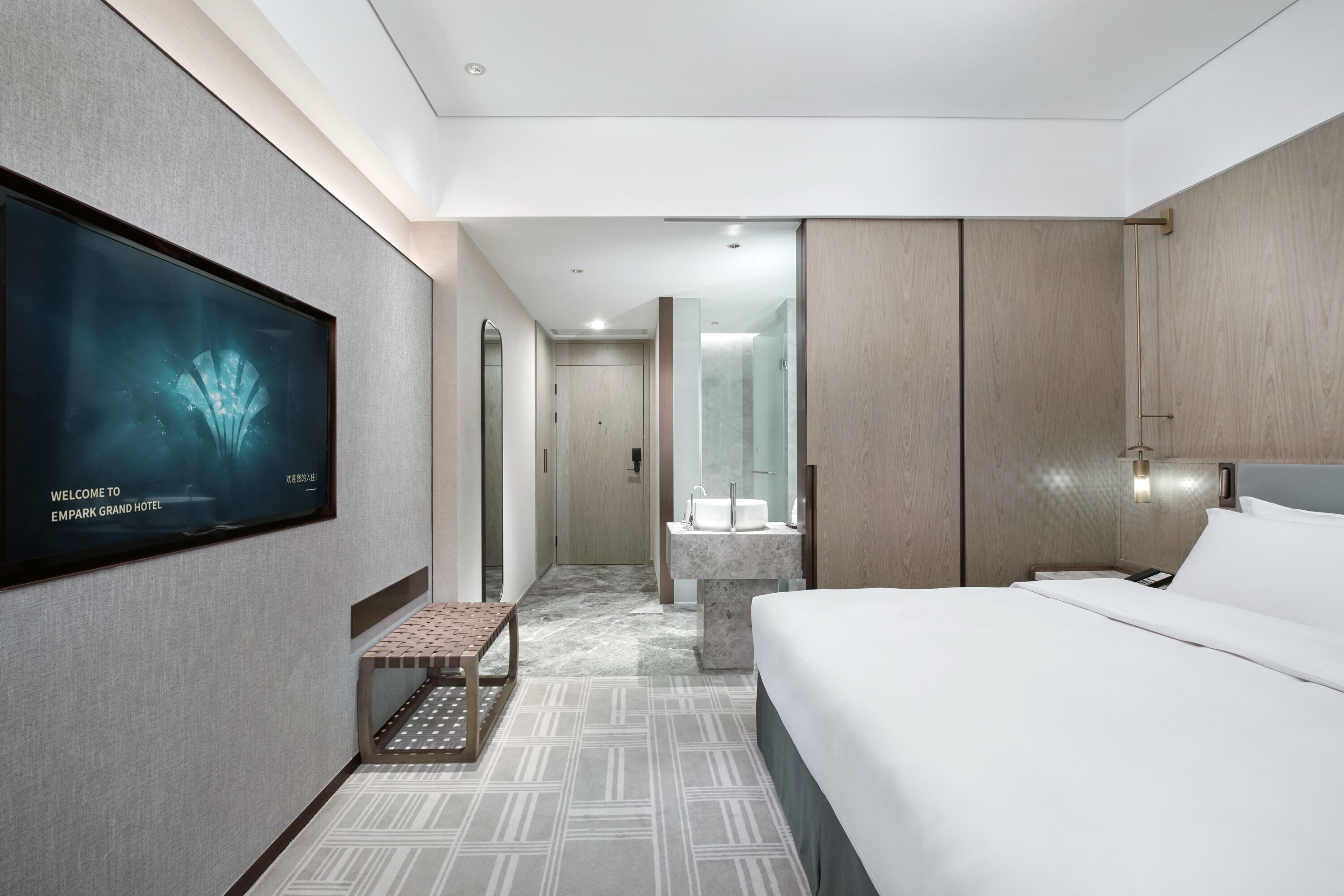 Camera d'albergo moderna con un letto grande, una TV a schermo piatto, un bagno con lavabo in marmo e un pavimento decorato.