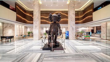 A spacious lobby with a marble floor, a central statue, and a seating area with a piano.