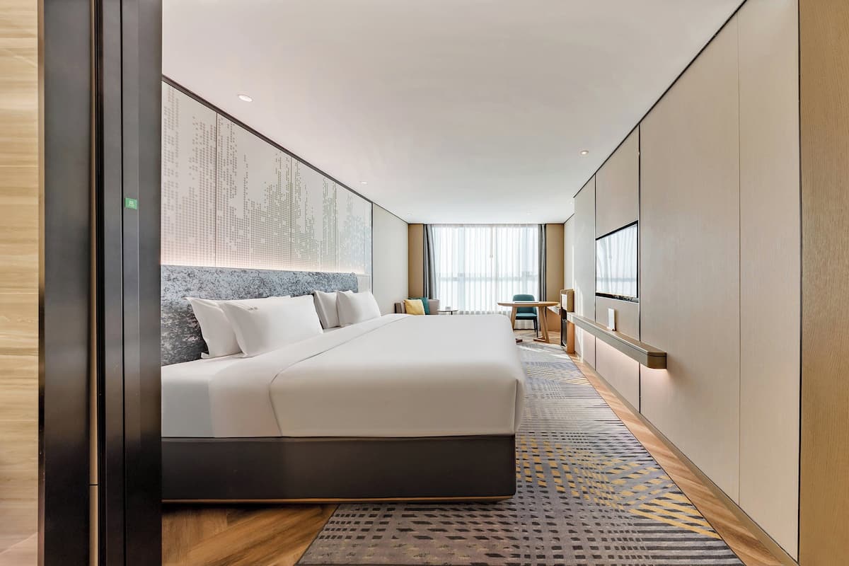 Ein modernes Hotelzimmer mit einem großen Bett, einem Schreibtisch und einem Fernseher.