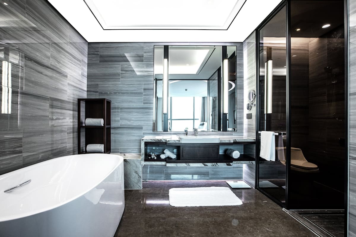 Ein modernes Badezimmer mit einer freistehenden Badewanne, einer Duschkabine und einem großen Spiegel über dem Waschbecken.