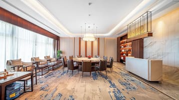 A modern hotel lobby with a round table, comfortable seating, and a reception desk.