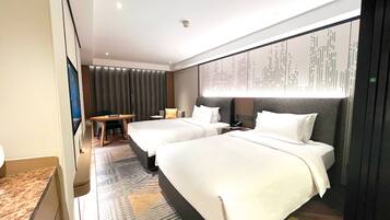 A hotel room with two beds, a desk, a chair, and a large window with curtains.
