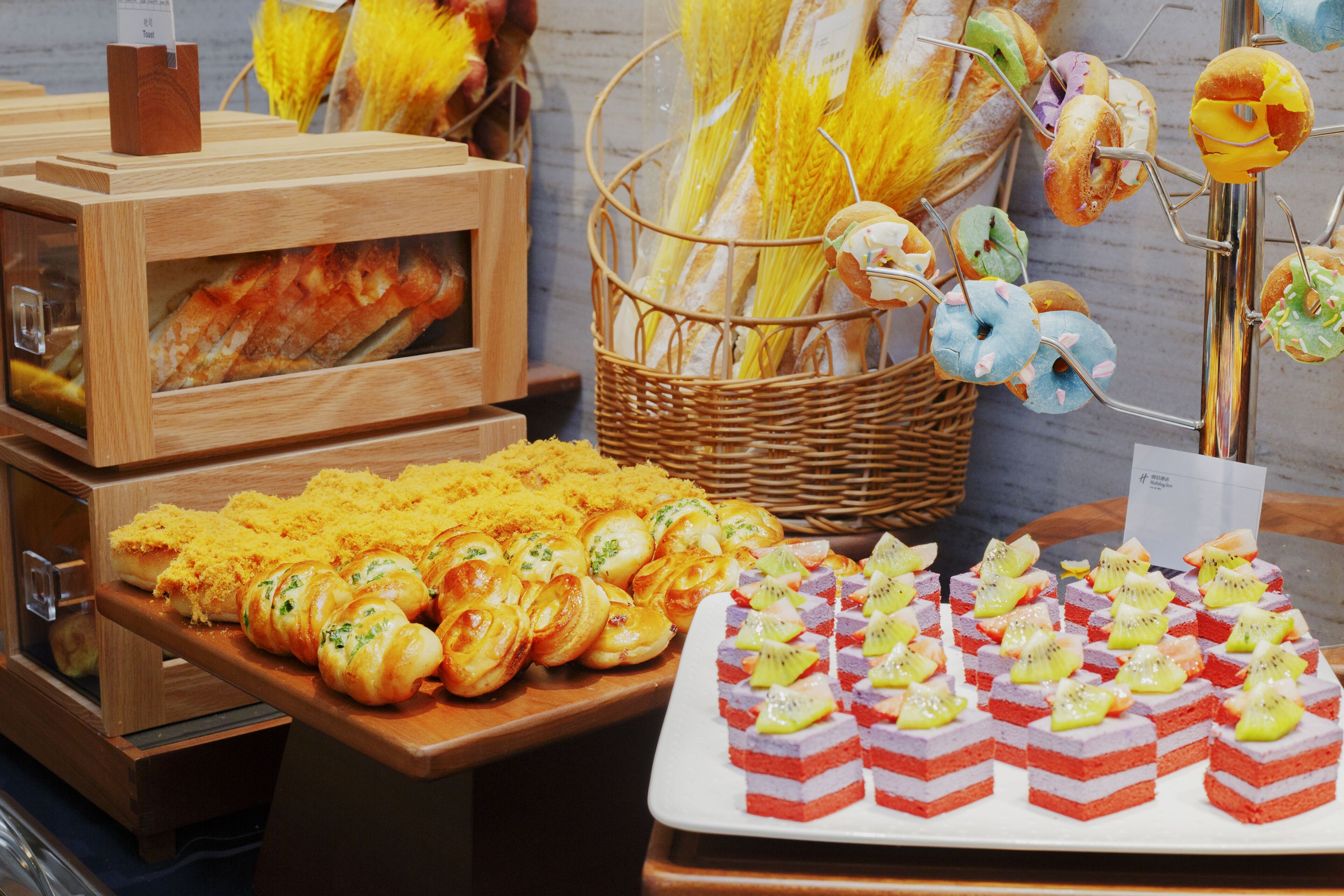 A buffet with various food items including bread, pastries, and fruit-topped desserts.