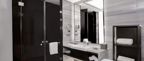A modern bathroom with a glass shower enclosure, a large mirror, a white bathtub, and a dark wood vanity.