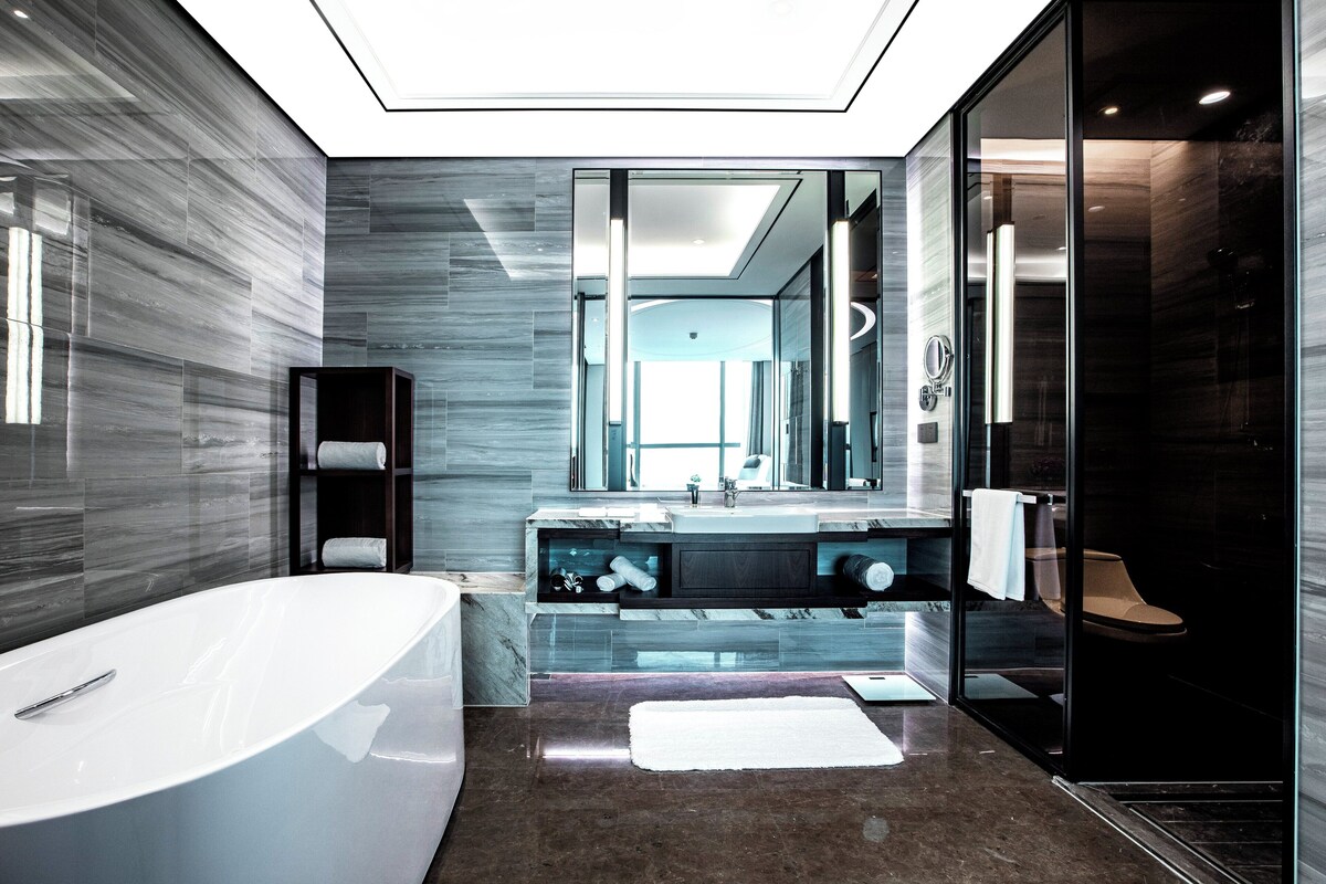A modern bathroom with a freestanding bathtub, a glass-enclosed shower, and a large mirror above the sink.