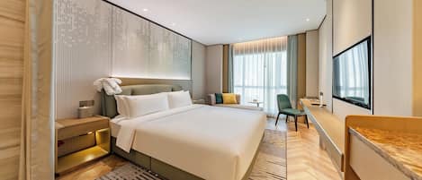 Una habitación de hotel moderna con una cama grande, un escritorio, una silla, un televisor y una ventana con cortinas.