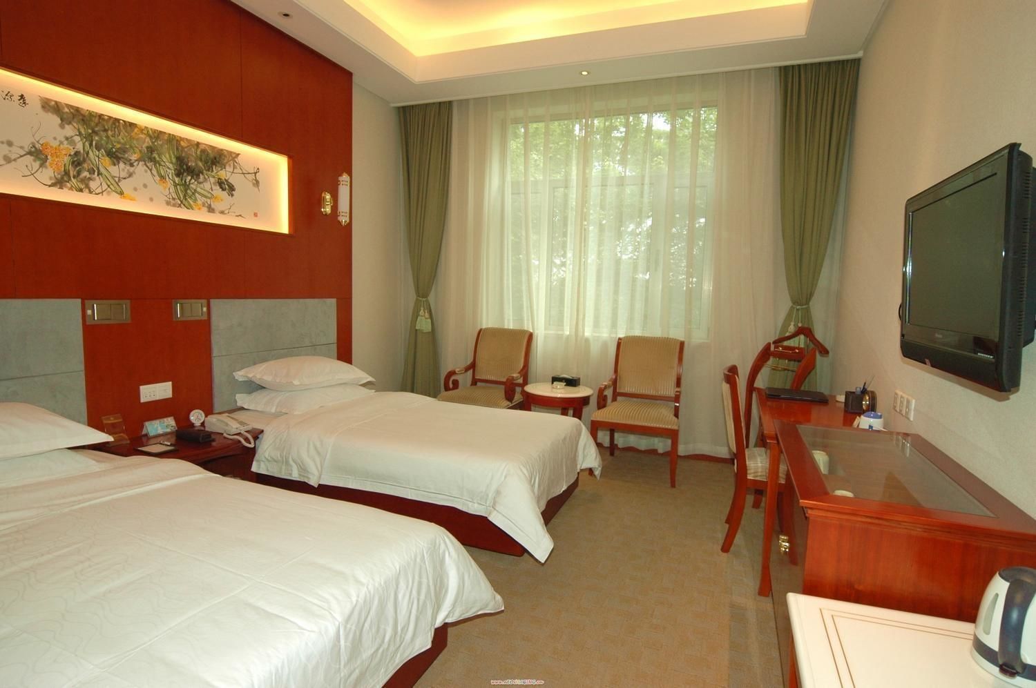 A hotel room with two beds, a desk, a chair, a television, and a painting on the wall.