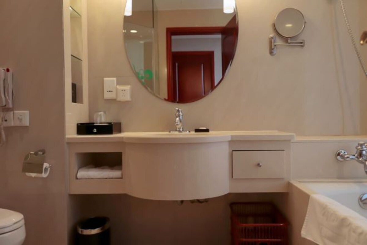 Une salle de bain équipée de toilettes, d’un lavabo, d’un miroir et d’une douche.