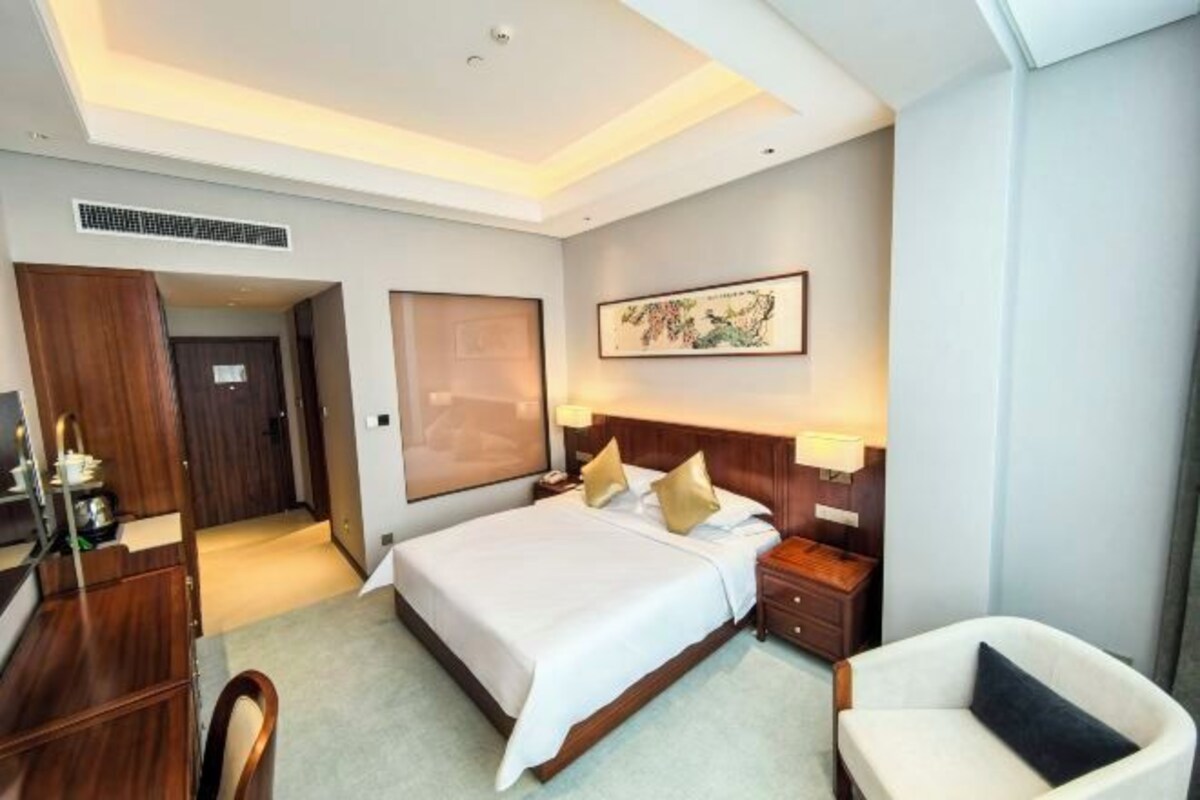 Une chambre d’hôtel avec un grand lit, des tables de chevet, un bureau et une chaise.