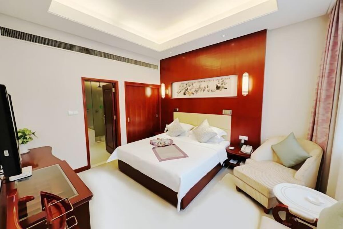 Une chambre d’hôtel avec un grand lit, un bureau, une chaise, un canapé et une télévision.