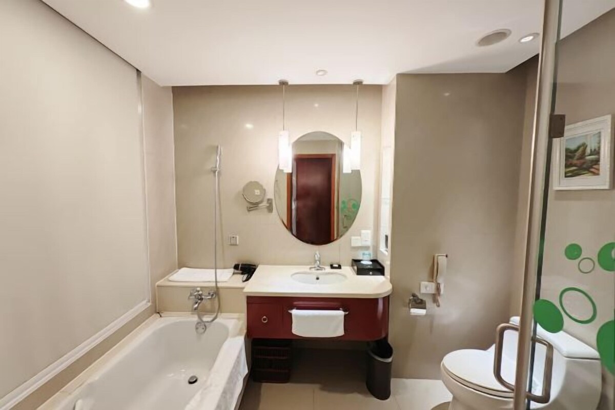 A modern bathroom with a bathtub, a sink with a mirror, and a toilet.