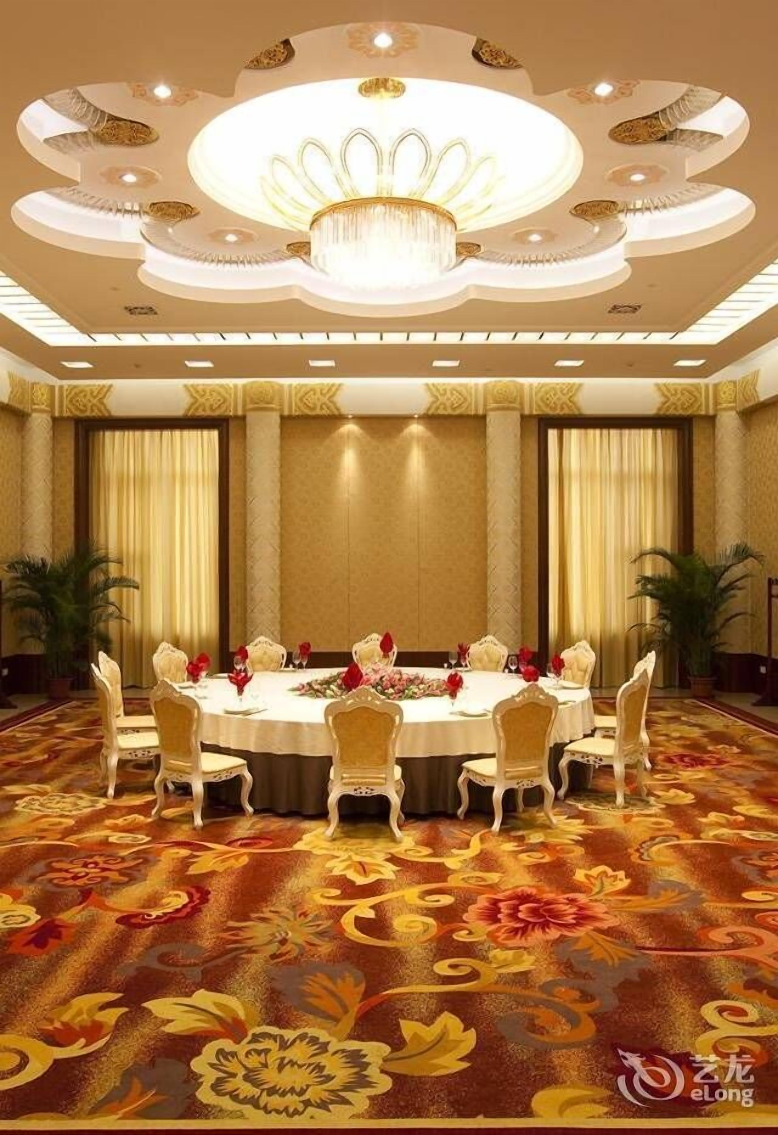 Un salón de conferencias con una mesa redonda, sillas blancas y una araña.