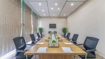 A conference room with a long table, chairs, a projector screen, and decorative plants.